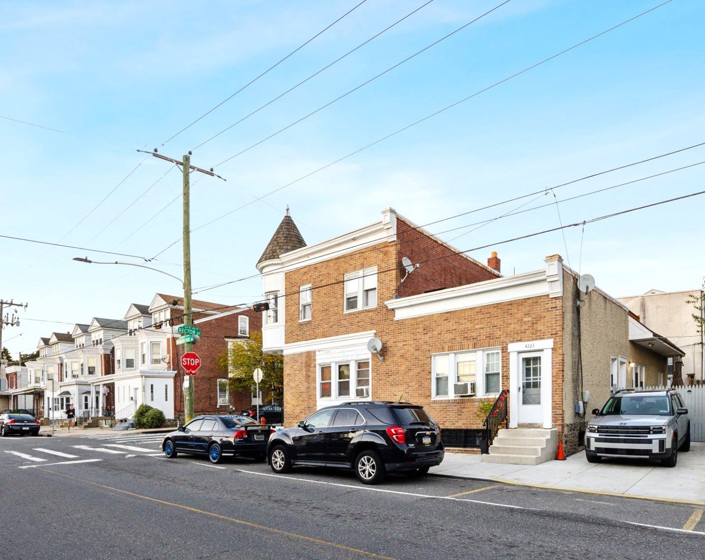 Cars parked on the side of a street in front of a brick building.